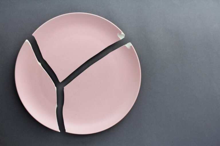 A broken pink ceramic plate on a gray background. view from above. The concept of diet, old things