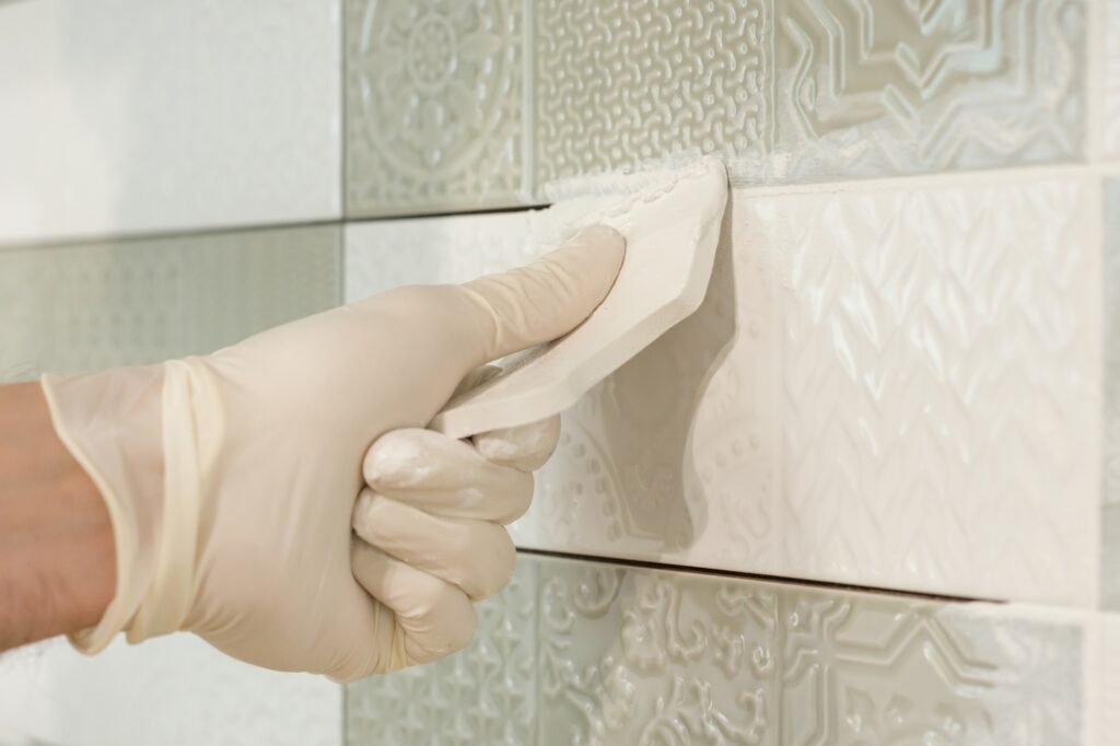 Closeup of tiler hand rubbing tile, Installing and grouting decorative finishes
