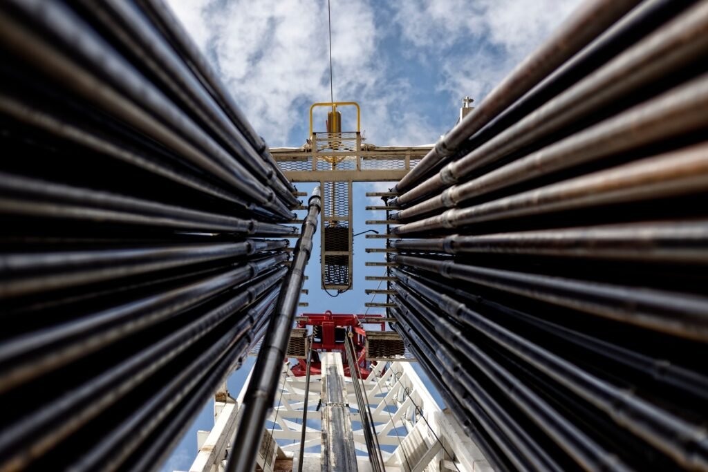 View of an oil rig from below, with a stack of drilling pipes in the foreground